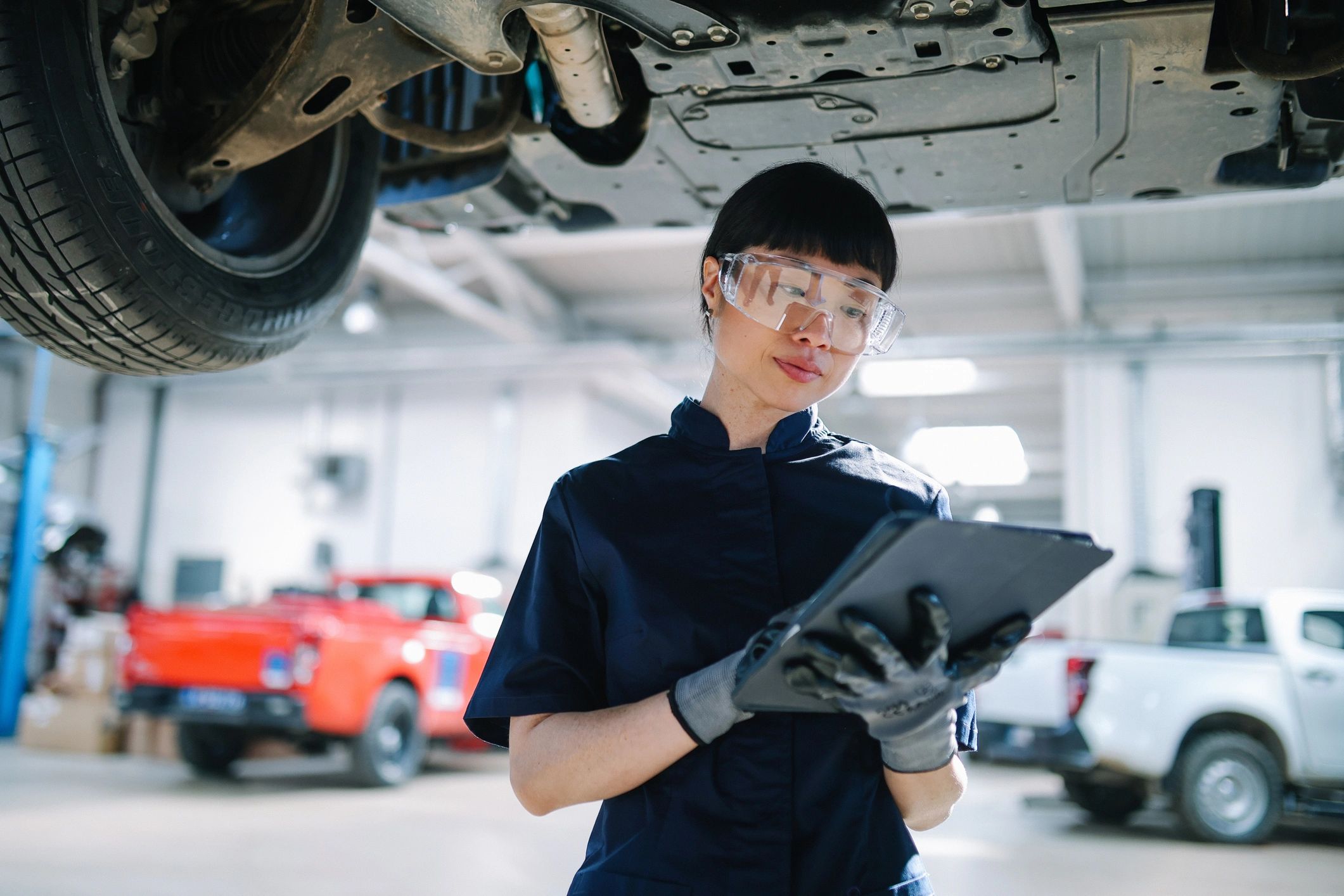 Technician inspecting a vehicle in a workshop using a tablet